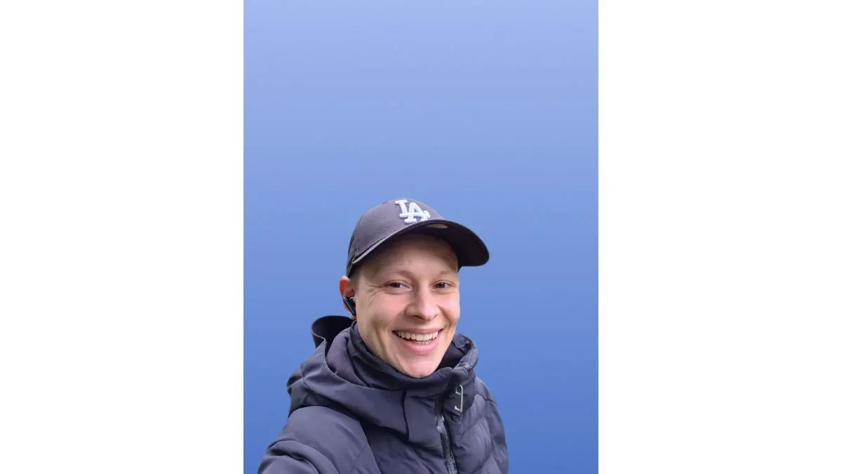Ein Selfie zeigt Alex vor einem einfarbigen, blauen Hintergrund.