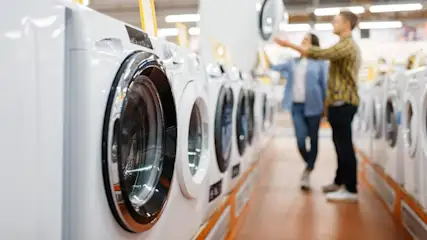 Ein zweitüriger, silberfarbener Kühlschrank mit einem Wasserspender ist vor einem grauen Hintergrund zu sehen.