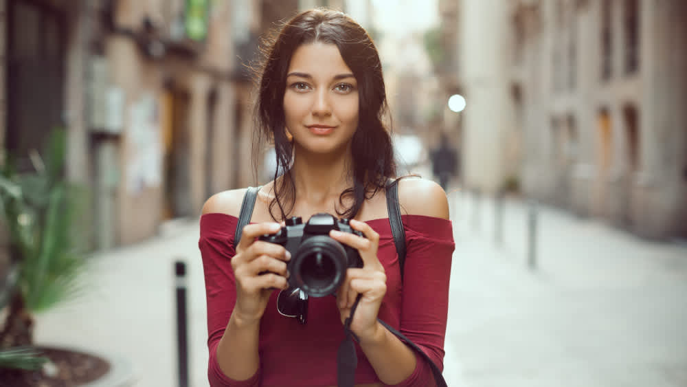 Eine Frau visiert mit einer Kamera an.