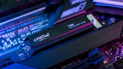 Eine Crucial T500 SSD auf einer Computer-Hauptplatine, beleuchtet in Blau- und Lilatönen.