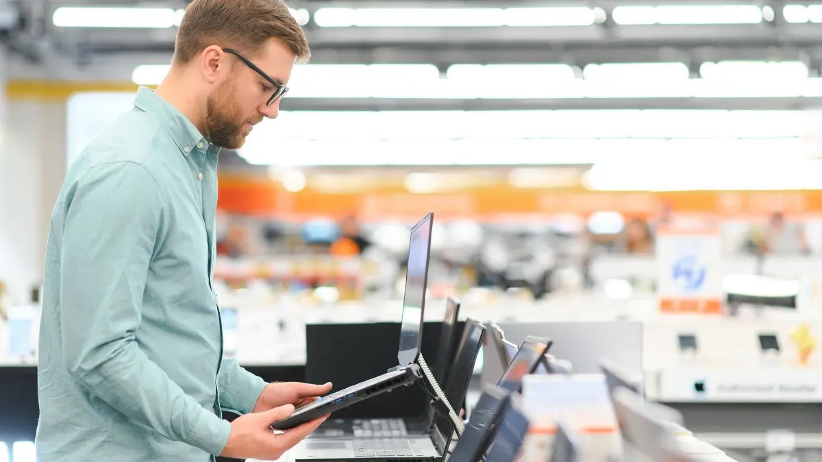 Ein Mann sieht sich einen Laptop in einem Fachgeschäft an.