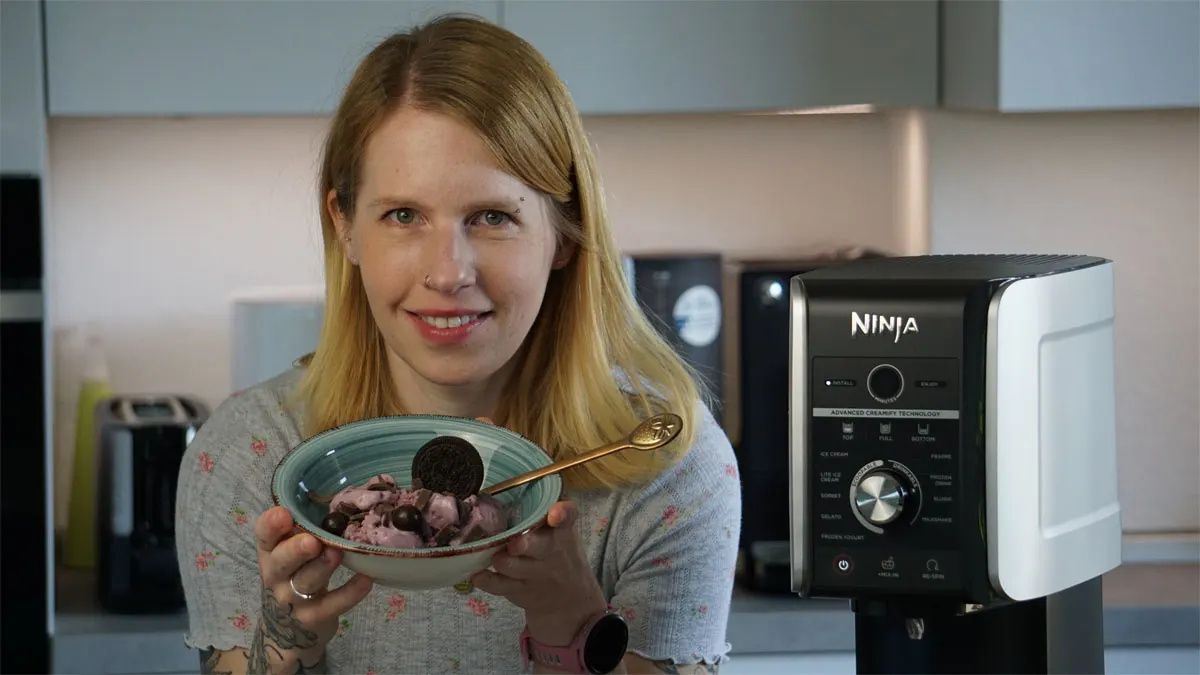 Franzi hält eine Schüssel mit Kirscheis und Schokolade in den Händen, neben ihr steht die Ninja Creami Deluxe.