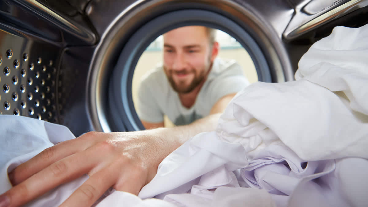 Ein Mann greift in einen Waschtrockner.