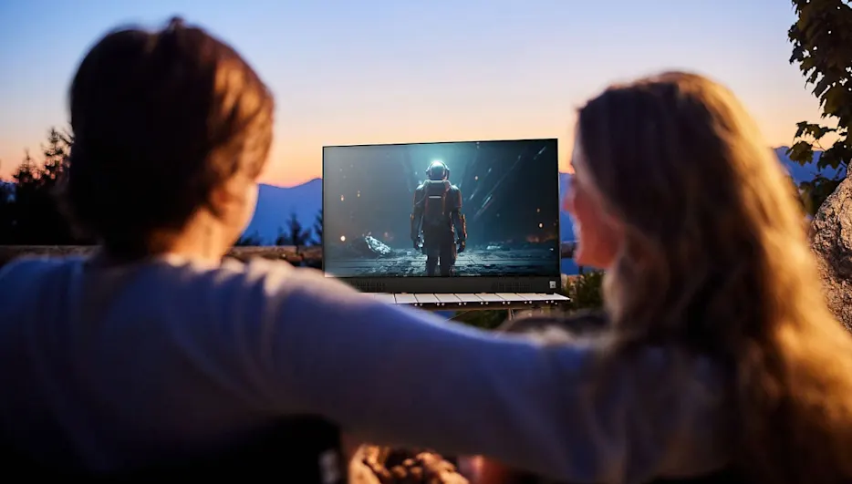 Ein Mann und eine Frau schauen auf dem PEAQ PTV 32GF-5025C-B unter freiem Himmel einen Film.