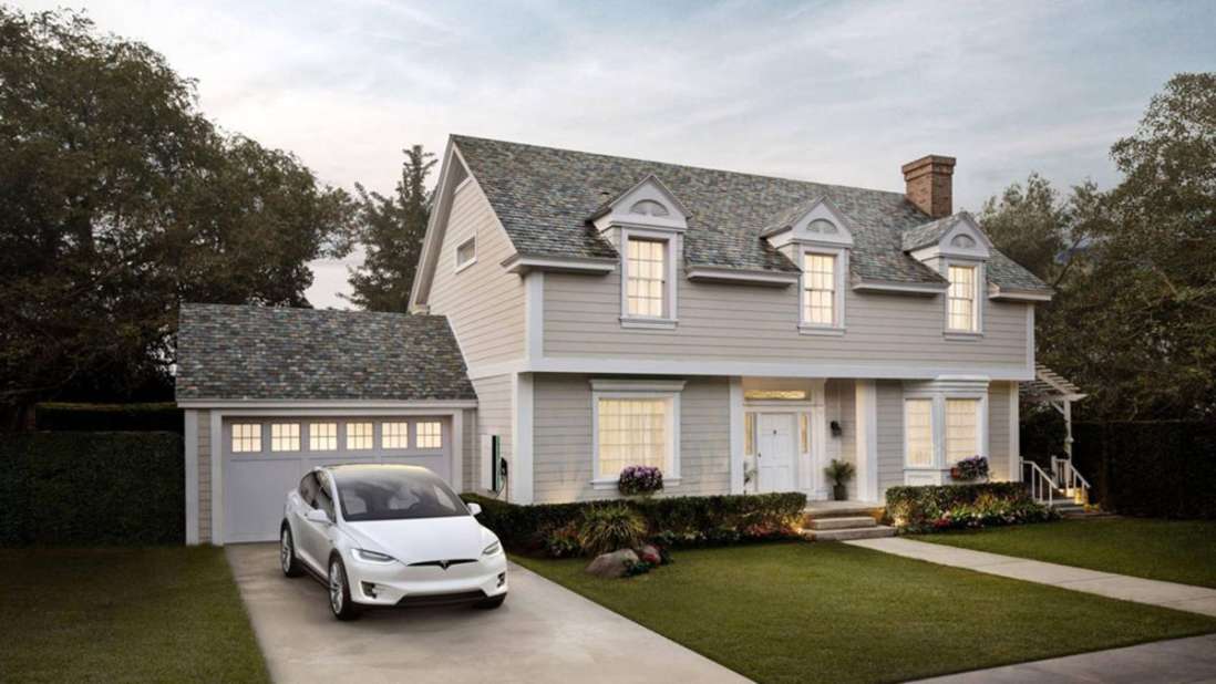 Ein Tesla-Auto steht vor einer Garage neben einem Haus.