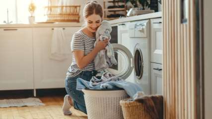 Frau füllt Waschmaschine mit Kleidung.