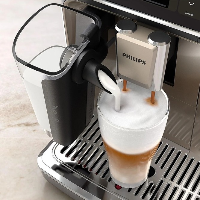Der PHILIPS EP5547/90 Serie 5500 Kaffeevollautomat schäumt Milch in ein Glas, während der Auslauf einen Kaffee einlässt; daneben steht ein angeschlossener Milchbehälter.