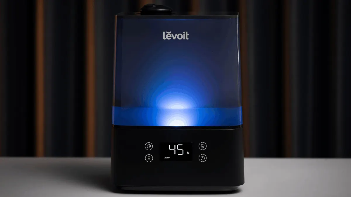 Der Luftbefeuchter Levoit Classic 300S Pro steht auf einem weißen Untergrund und leuchtet blau.