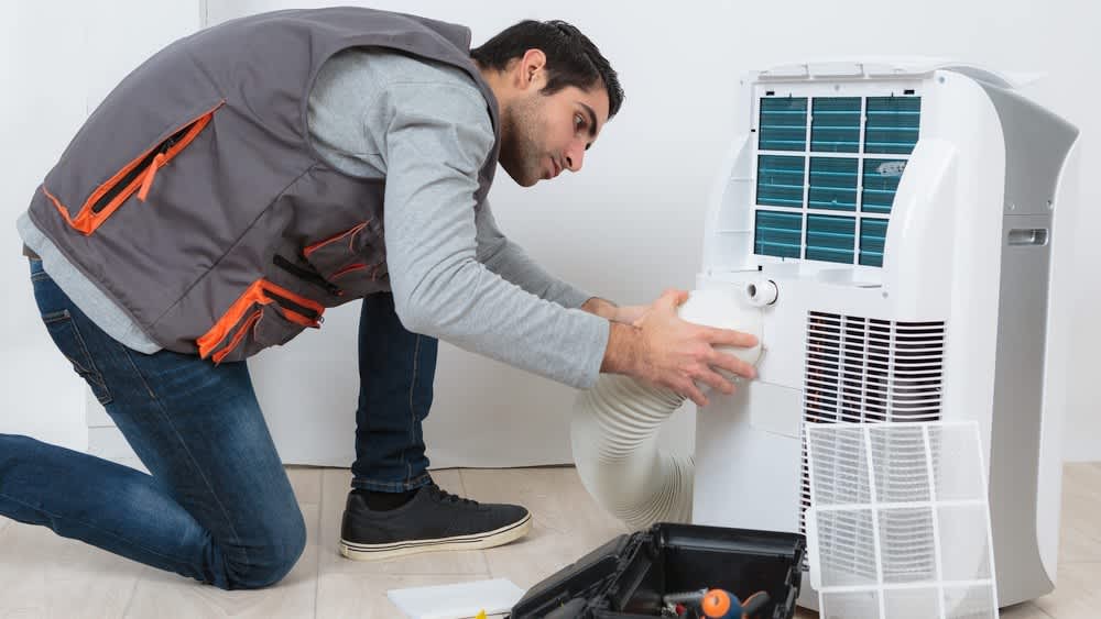 Ein Elektriker begutachtet eine Klimaanlage.