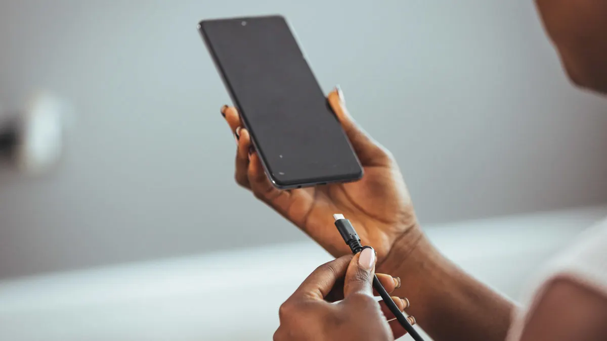 Eine Person steckt ein Ladekabel an ein Smartphone in der Hand.