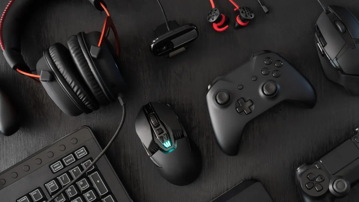 Eine Tastatur, Gaming-Mäuse, Gamepads und Headsets liegen auf einer schwarzen Oberfläche.