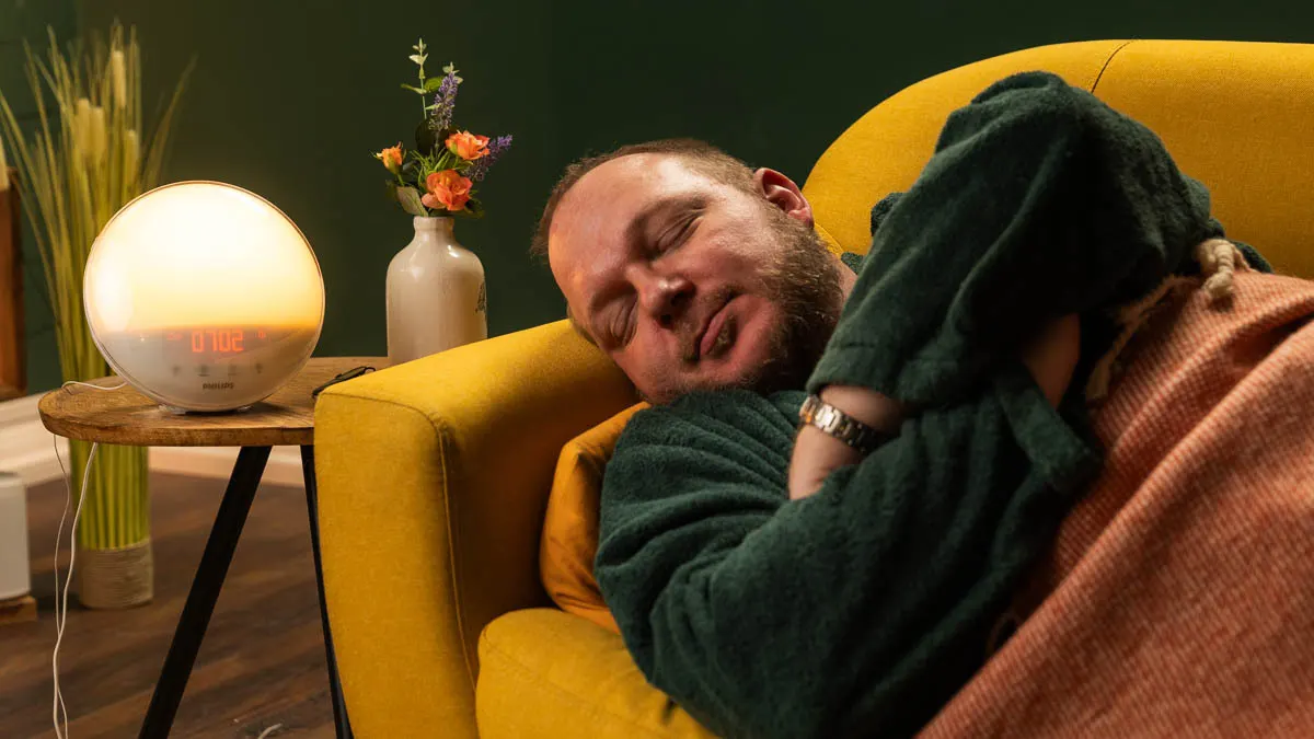 Andreas liegt auf einer Couch, daneben steht ein Philips-Lichtwecker auf einem Beistelltisch.