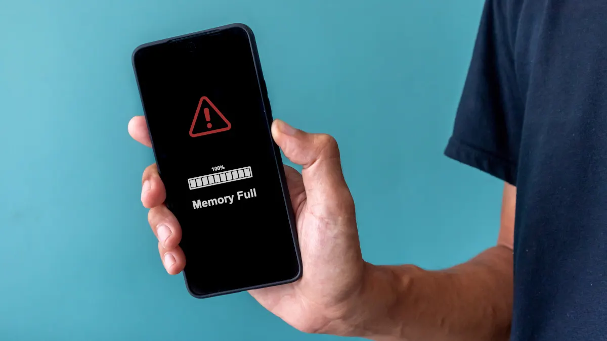 Ein Mann zeigt ein Smartphone, auf dessen Display ein Warnzeichen und der Text „Memory Full“ steht.
