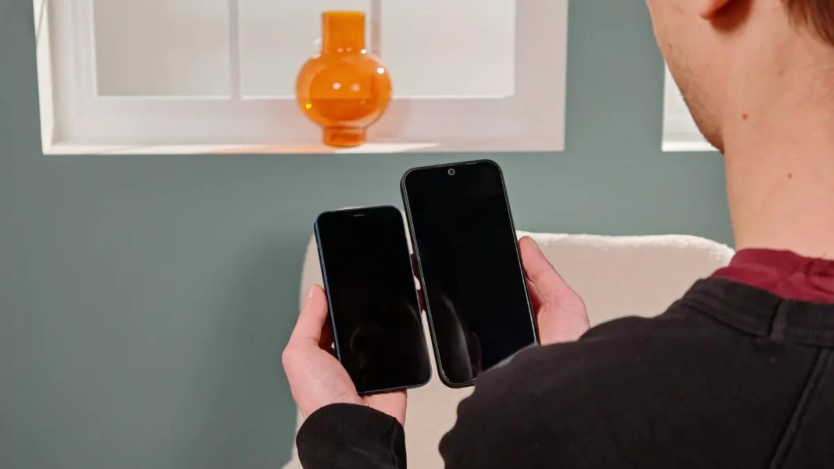 Alex hält ein iPhone 12 mini (links) und ein Nothing Phone (2a) Plus nebeneinander und vergleicht die Größen.