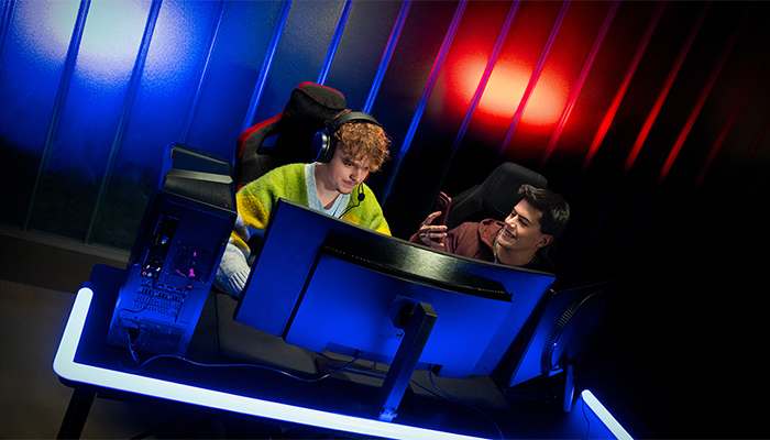 Zwei Profi-Gamer beim Zocken vor einem sehr großem Gaming-Monitor.