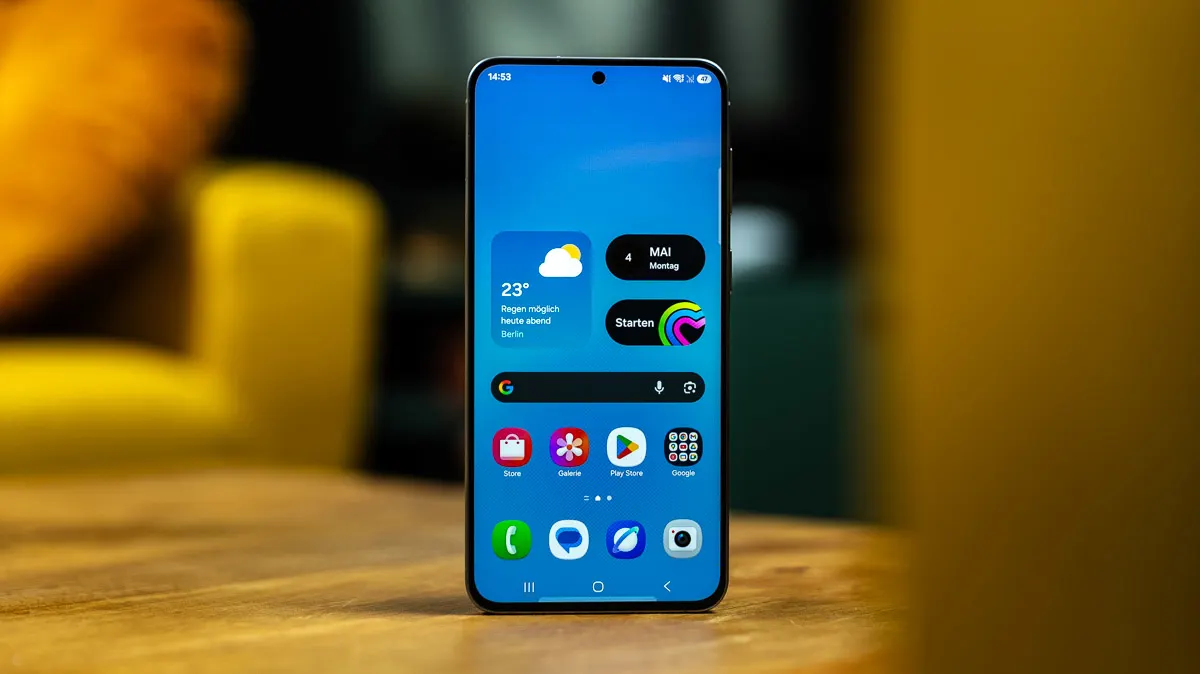Das Samsung Galaxy A57 steht mit eingeschaltetem Display auf einem Tisch.