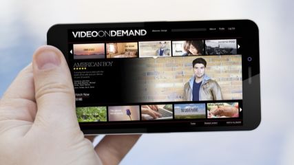Hand hält ein Smartphone auf dem ein Videoportal zu sehen ist