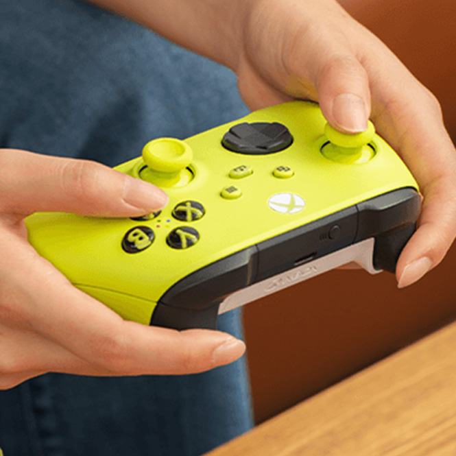 Eine Person hält einen gelben Xbox-Controller mit schwarzen Akzenten in ihren Händen.