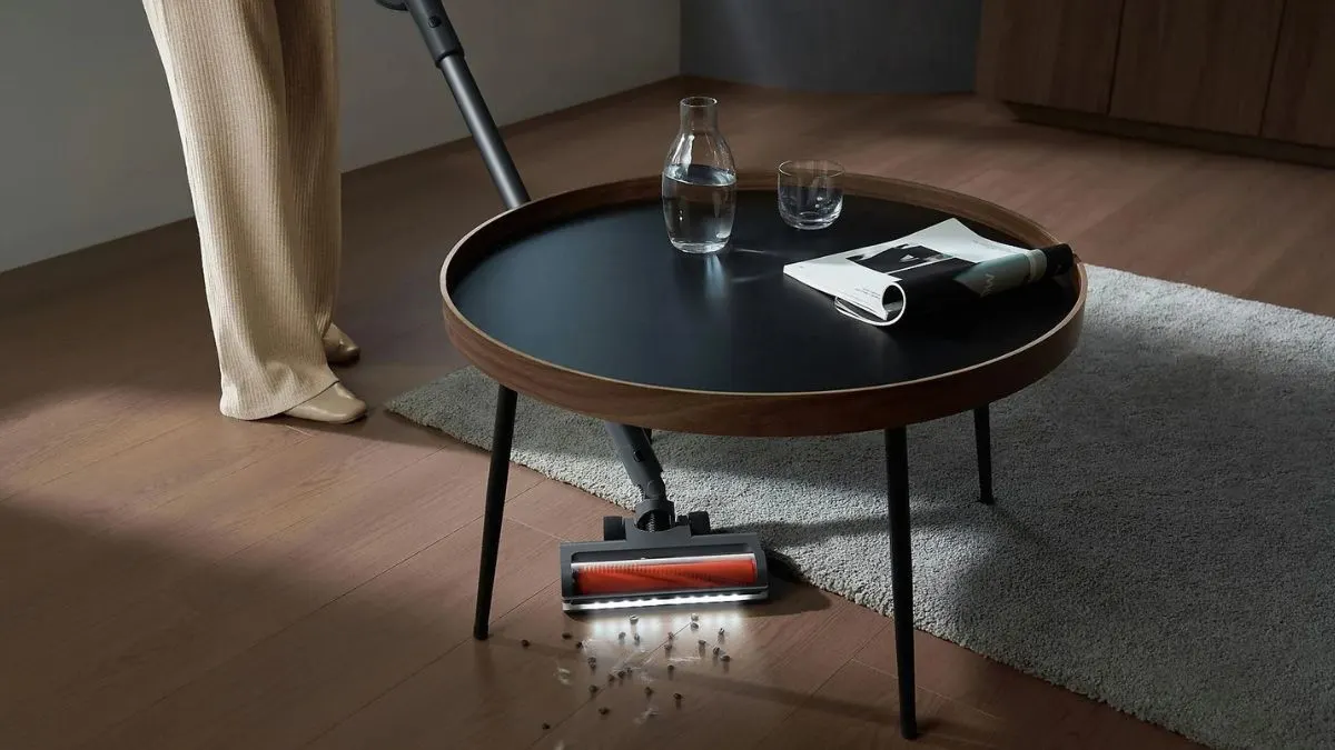 Eine Person saugt unter einem Wohnzimmertisch mit dem Akku-Staubsauger Xiaomi G20 Max.