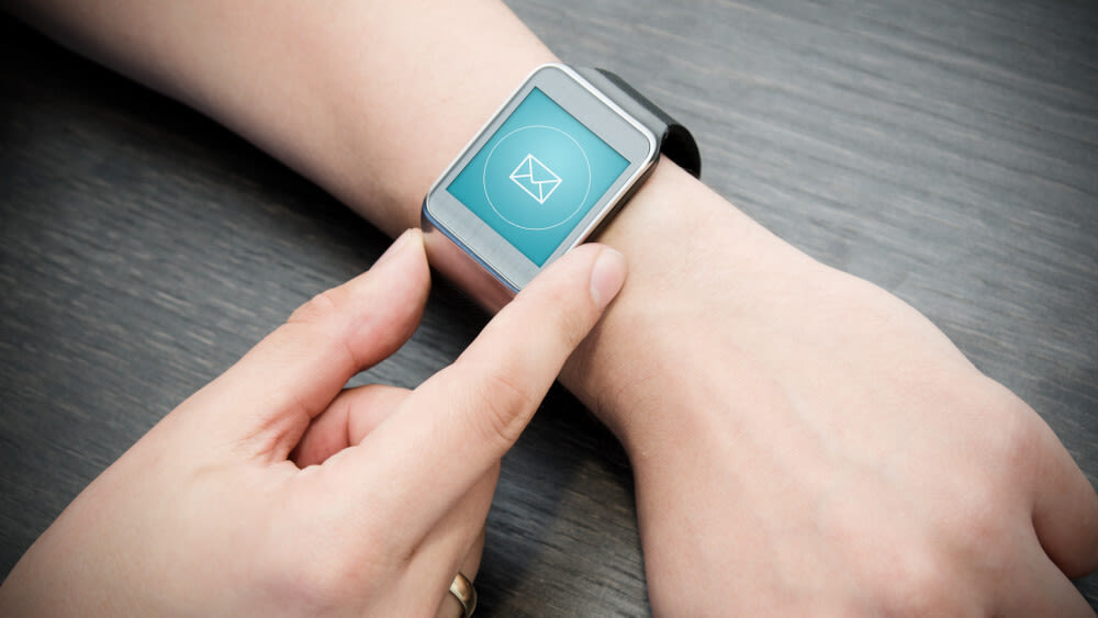 Eine Smartwatch auf einem Frauenarm, auf dem Bildschirm ist ein E-Mail-Icon zu sehen.