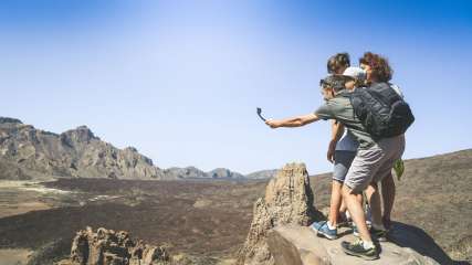 Eine Familie wandert in den Bergen und macht ein Selfie mit einer Action-Cam.