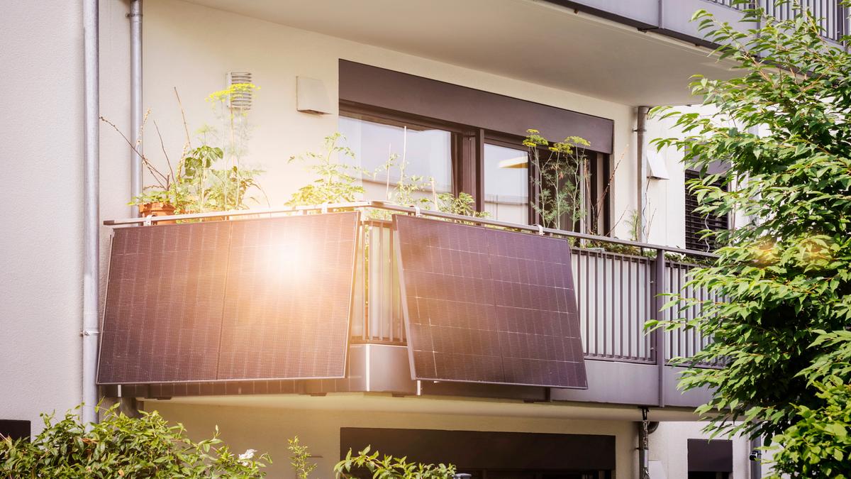 Ein Balkonkraftwerk ist an der Ecke des Geländers auf einem Balkon befestigt.