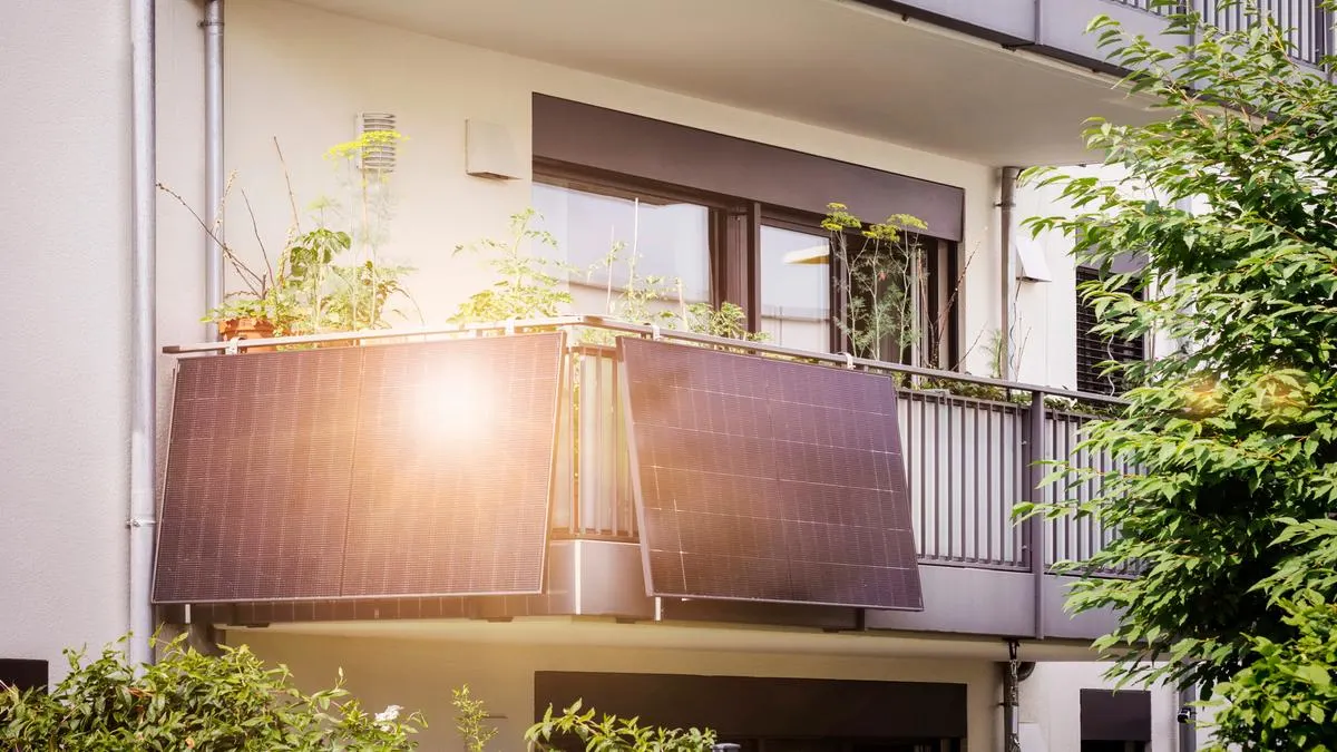 Ein Balkonkraftwerk ist an der Ecke des Geländers auf einem Balkon befestigt.