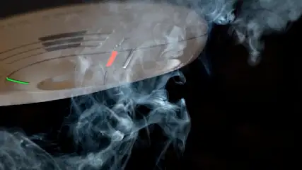 Ein Rauchmelder mit einer grünen LED ist von Rauch umgeben, der sich vor einem schwarzen Hintergrund abhebt.
