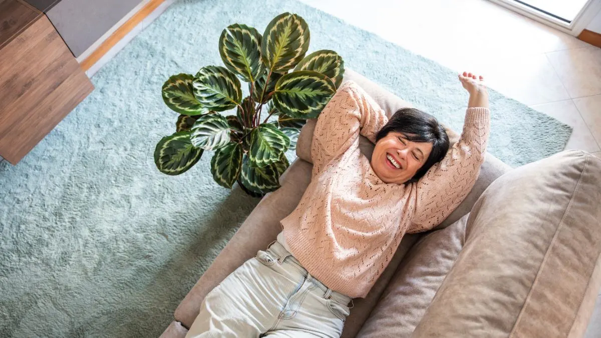 Eine Frau liegt auf dem Sofa und lächelt.