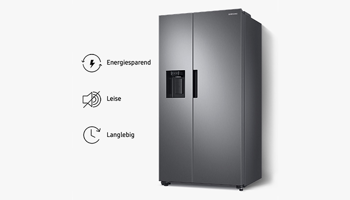 Ein grauer Samsung Side-by-Side-Kühlschrank mit einem schwarzen Wasserspender auf einer Tür vor einem weißen Hintergrund.