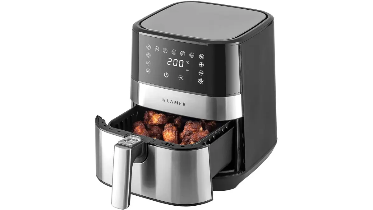 Ein schwarzer und silberfarbener Airfryer mit digitaler Anzeige und herausgezogener Schublade, die mit Speisen gefüllt ist.