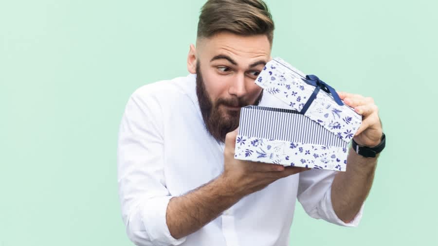 Mann mit Bart öffnet blau-weiße Geschenkbox