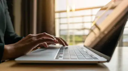 Eine Person tippt auf einem Laptop.