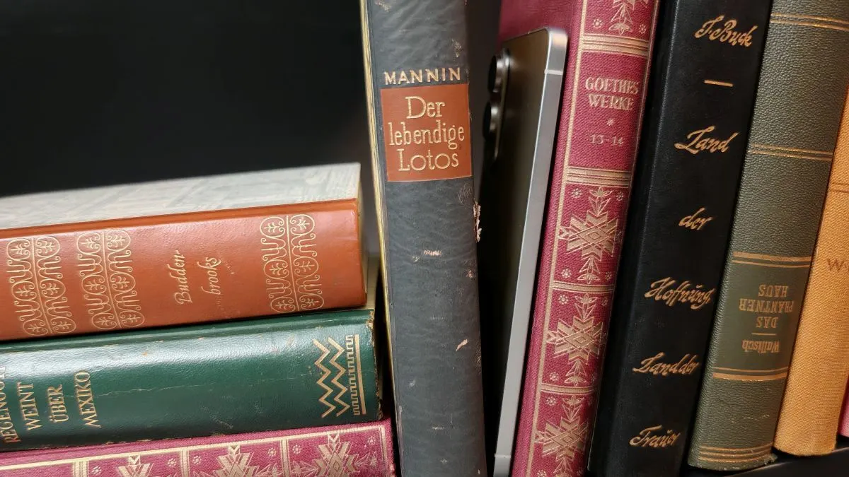 Das Galaxy S25 Edge steht neben anderen Büchern in einem Bücherregal.