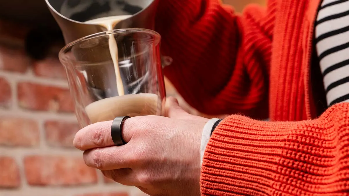 Franzi trägt den Ultrahuman Ring Air am linken Zeigefinger und füllt Milchshaum in ein Glas.