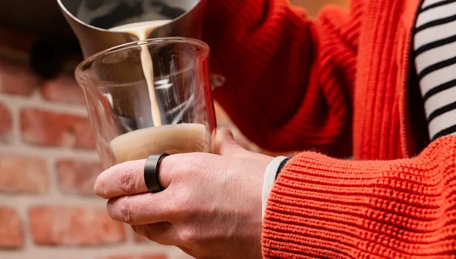 Franzi trägt den Ultrahuman Ring Air am linken Zeigefinger und füllt Milchshaum in ein Glas.