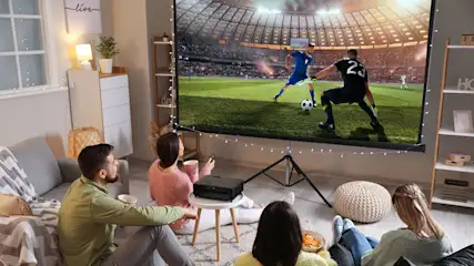 Familie schaut Fußball mit einem Beamer auf einer Leinwand