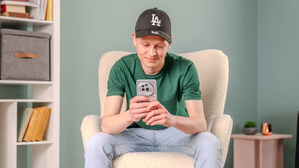 Alex sitzt auf einem Sessel und guckt auf das Nothing Phone (3a) Pro.