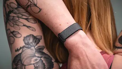 Franzi dehnt ihre Schulter und trägt dabei das Fitbit Air am linken Handgelenk.