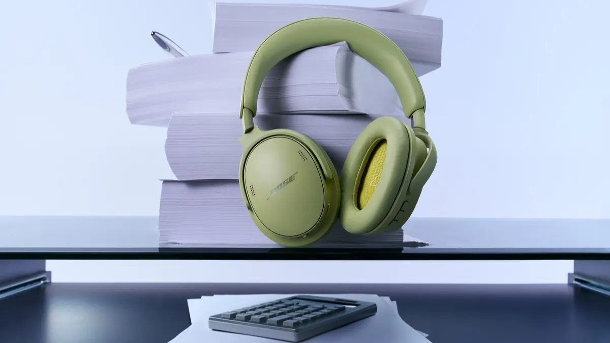 Der Bose QuietComfort Kopfhörer (2. Gen.) hängt an einem Papierstapel auf einem Schreibtisch.