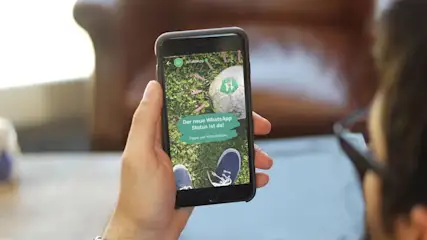 Ein Mann guckt sich einen WhatsApp-Status auf dem Handy an.
