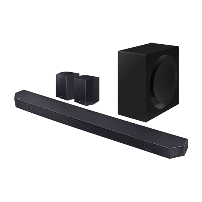Eine schwarze Soundbar liegt vor zwei kleinen Lautsprechern und einem Subwoofer auf weißem Grund.