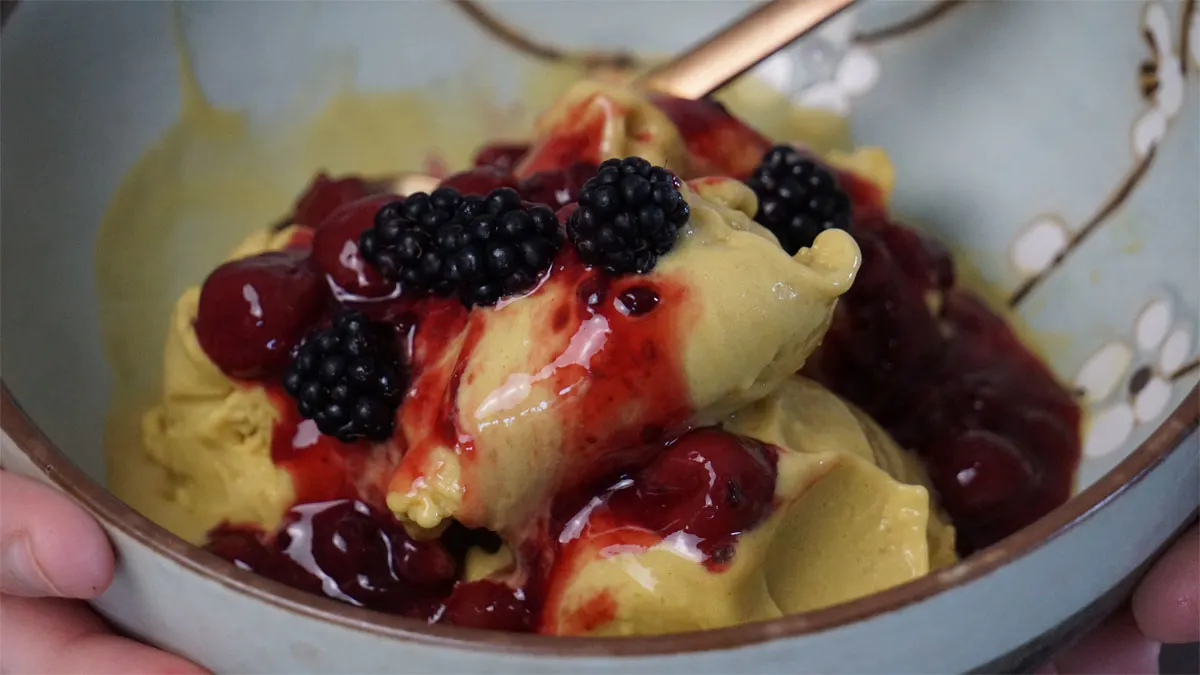 Mangosorbet mit roter Grütze und Brombeeren ist in einer Schüssel angerichtet.