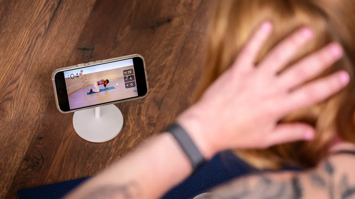 Franzi trägt das Fitbit Air und folgt einer Mobilitätsübung aus der Health-App-Mediathek.