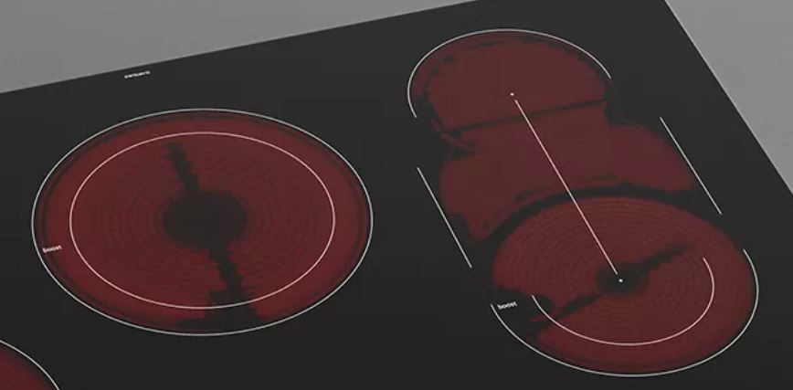 Ein schwarzes Kochfeld mit zwei roten Heizelementen, umrandet von weißen Markierungen.