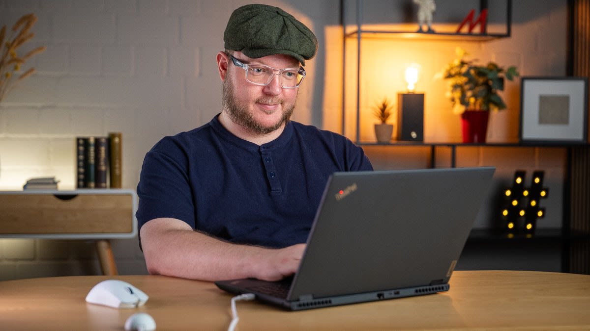 Andreas sitzt vor einem schwarzen ThinkPad, an das ein weißer USB-Dongle mit einem Kabel angeschlossen ist. Neben ihm liegt die kabellose Razer Viper V4 Pro.