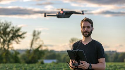 Ein Mann steuert eine fliegende Drohne.