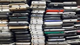 Alte Handys und Smartphones liegen zu mehreren Türmen nebeneinander aufgestapelt.