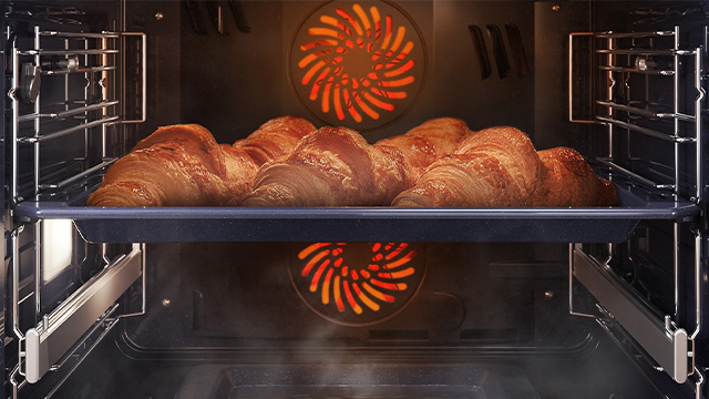 Egy tepsi croissant-okkal a sütőben.