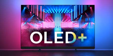 Ein schwarzer OLED+ Fernseher zeigt eine Bühne mit blauen und pinken Lichtern. Weiße Buchstaben stehen im Vordergrund. Der Hintergrund ist pink und blau.